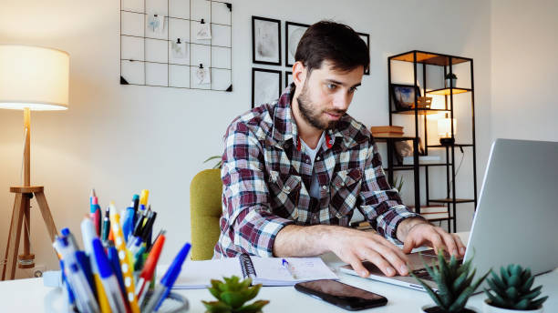 istock Young Caucasian entrepreneur working from home on laptop and dealing with finances 2176972939