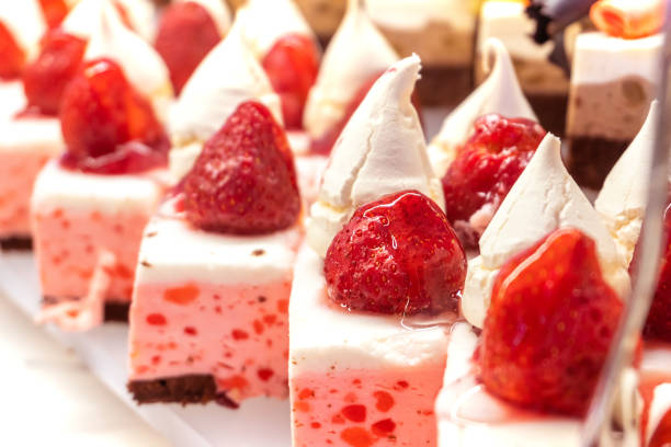 Strawberry mousse pastries topped with whipped cream and fresh strawberries on a restaurant table. Close-up. Selective focus.