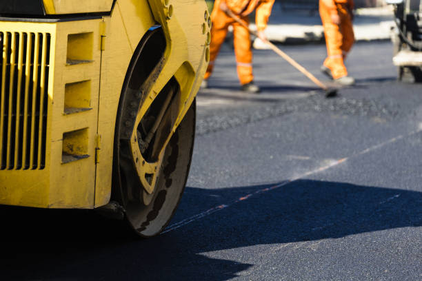 istock A road construction crew repairs asphalt in bright orange uniforms while a heavy yellow roller compacts freshly laid pavement, creating a smooth surface 2176979055