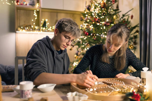istock Teenagers decorating gingerbread house pieces with icing and sprinkles 2176981008