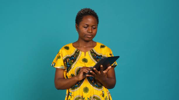 istock Natural cute girl browsing internet on a tablet against blue background 2176986286