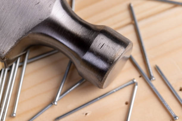 Close-up of man hammering a nail on piece of wood