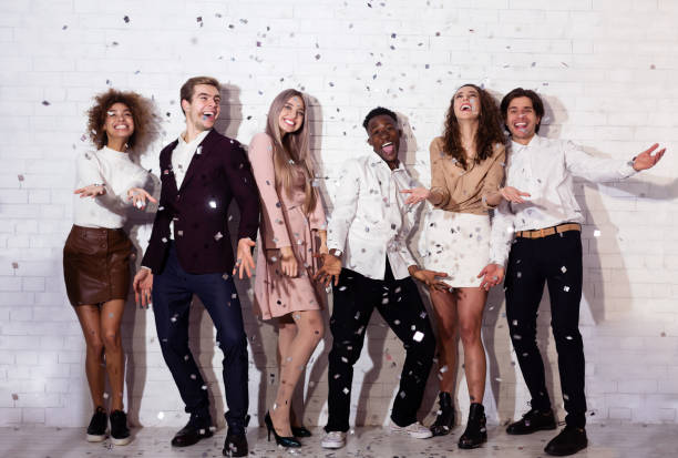 A group of friends having fun celebrating during the night accompanied by confetti and joyful expressions, showcasing camaraderie and a festive atmosphere.