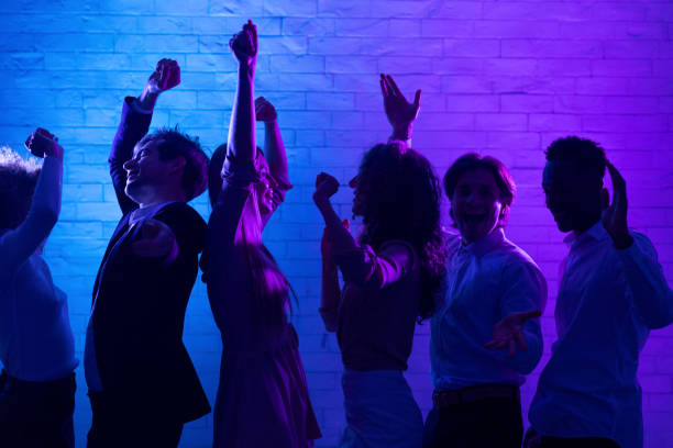 Group Of Cheerful Young People Dancing Having Fun At Corporate Night Party Indoor. Low Light