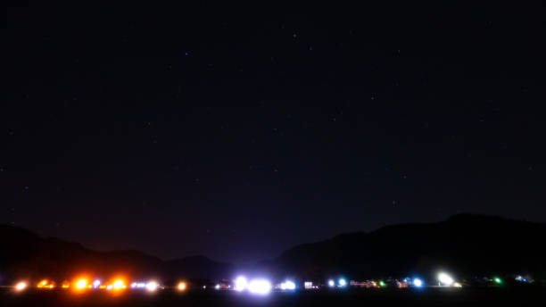 City lights create a warm, glowing contrast against the dark night sky, while the stars shimmer faintly above, blending the urban with the cosmic.