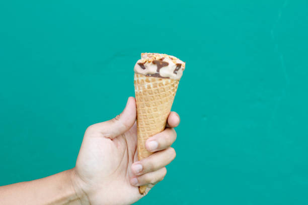 istock man's hand holding ice cream, on a green background 2177018291