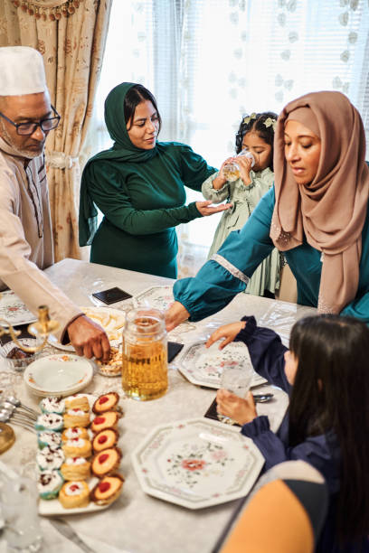 istock Woman serving drinks to her family at the dining table during an Eid feast 2177023054