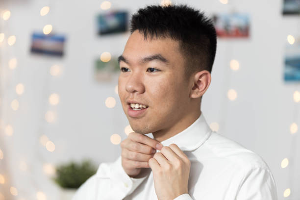 istock A young man is adjusting his tie while wearing a white dress shirt and tie 2177033436