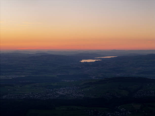 A beautiful sunset over two lakes, casting warm hues across the sky and the countryside below, creating a peaceful and scenic evening atmosphere.
