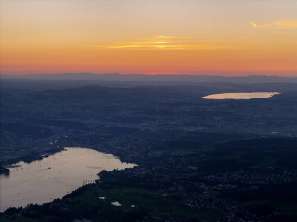 A beautiful sunset over two lakes, casting warm hues across the sky and the countryside below, creating a peaceful and scenic evening atmosphere.