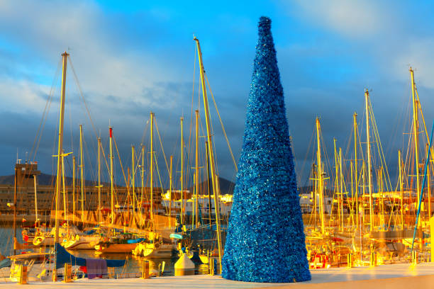 Decorative Christmas Tree in the Port. Christmas tree adorned with sparkling ornaments and twinkling lights, yachts on background