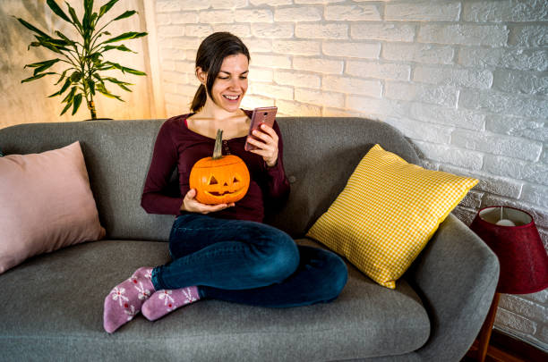 istock Woman using phone while holding jack-o-lantern pumpkin 2177053831