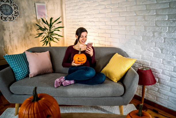 istock Woman using phone while holding jack-o-lantern pumpkin 2177054511