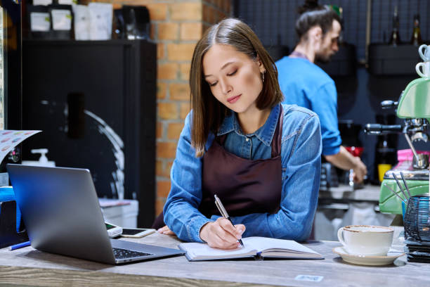 istock Young woman coffee shop worker in apron using laptop computer at bar counter 2177055237
