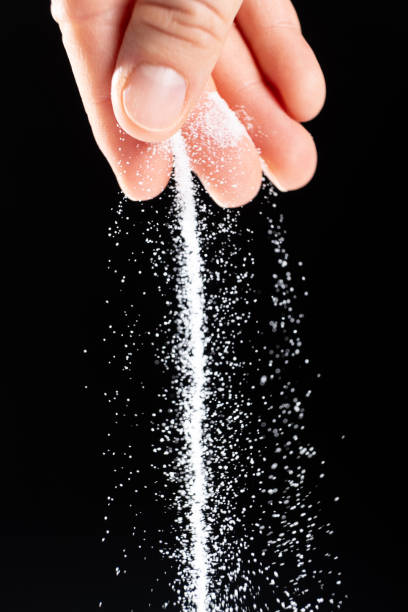 istock Hand pouring white stone salt finely ground, black background. 2177059250
