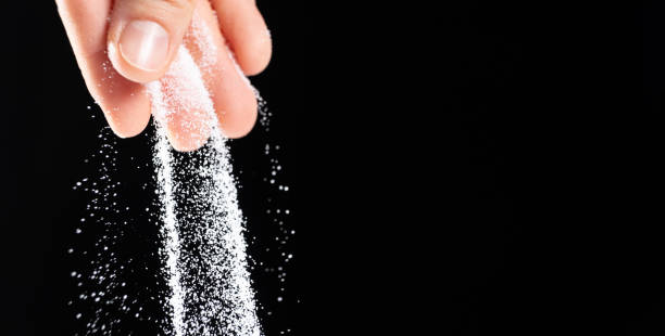 istock Hand pouring white stone salt finely ground, black background copy space for text 2177059252