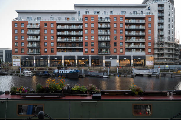 16.08.2024 Leeds, UK. Modern apartments overlook the serene Leeds Dock, with moored canal boats adding a touch of charm to the urban waterfront. A peaceful scene blending contemporary living with riverside tranquility.