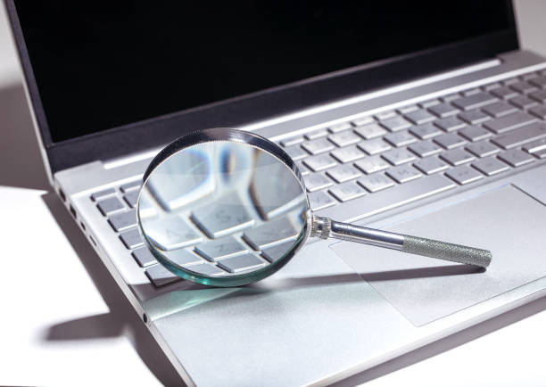 Close up photo of magnifying glass on top of computer keyboard