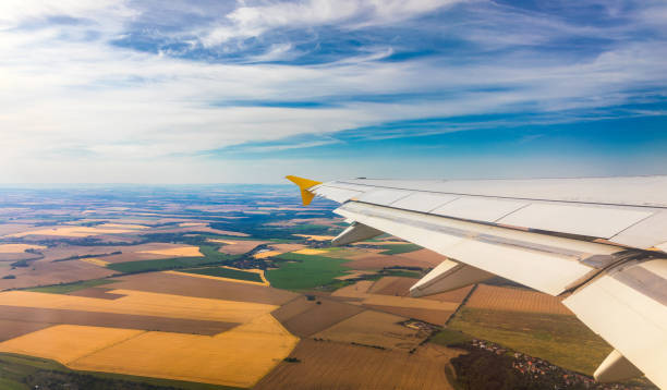 istock Airplane windows view above the earth on landmark down. View from an airplane window over a wing flying high above farmlands and fields. View from window of plane airplane flying. 2177065841
