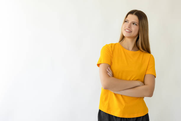 Young beautiful woman in yellow t-shirt looking up and smiling