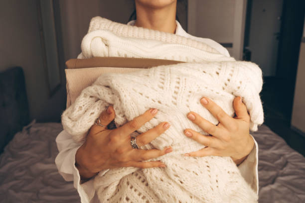istock Woman Holding Folded Knit Sweaters in Hands 2177066442