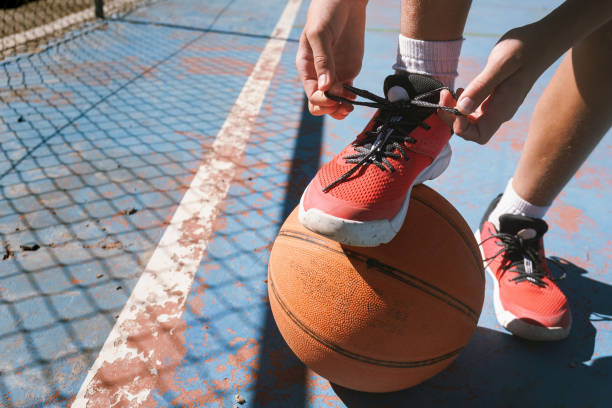 istock A person is tying their shoe while standing next to a basketball 2177068836
