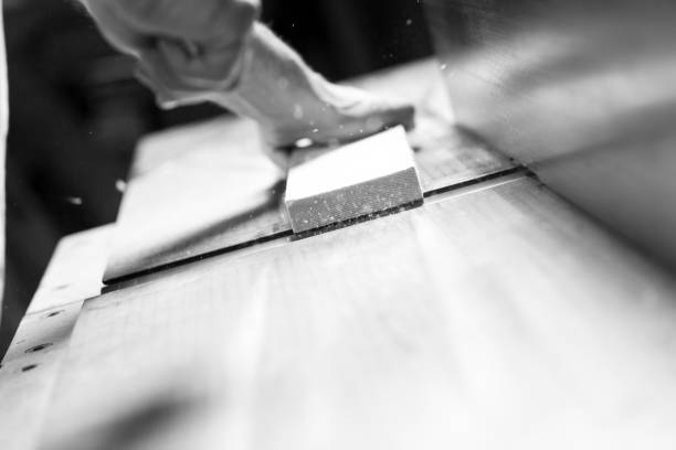Carpenter is smoothing a piece of wood with a bench plane in a woodworking workshop. - black n white -