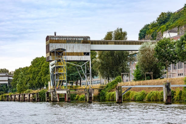 Industrial complex with abandoned and ruined bulk cargo terminal, storage tower on bank of Meuse river, used for loading and unloading cargo ships, Maastricht, South Limburg, Netherlands