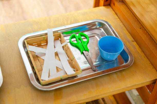 istock Green scissors with white paper strips on a tray 2177079091