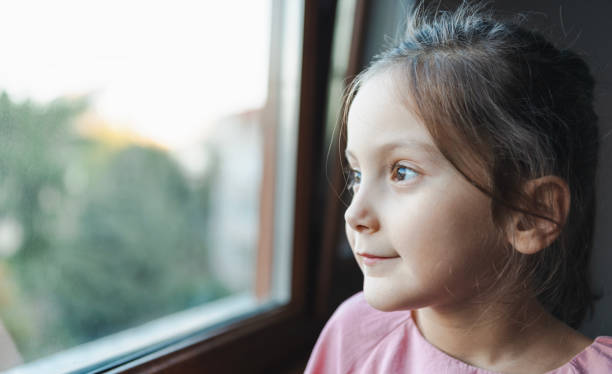 istock Smiling Girl Looking Out the Window 2177079521