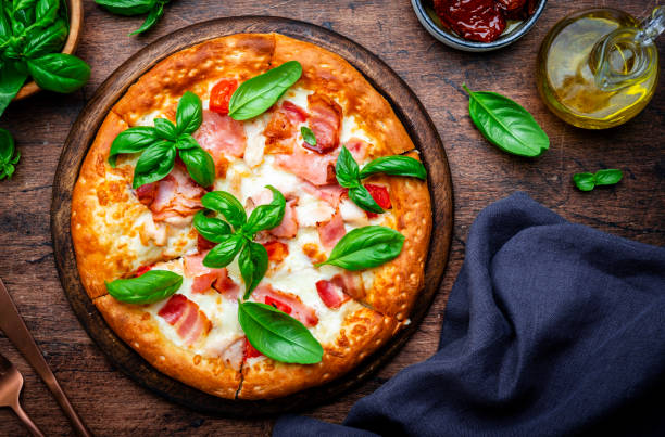 istock Small hot pizza with pancetta, mozzarella, tomato and basil on wooden background, top view 2177084395