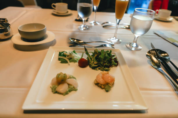 Set of dishes from: Caesar salad, grilled eggplant steak, vegetable salad with poached egg and Striploin steak in a wine sauce. Top view of woman having sitting at the wooden table
