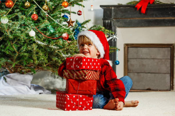 istock Happy boy sit, hold his Christmas present wrapped in red paper 2177087713