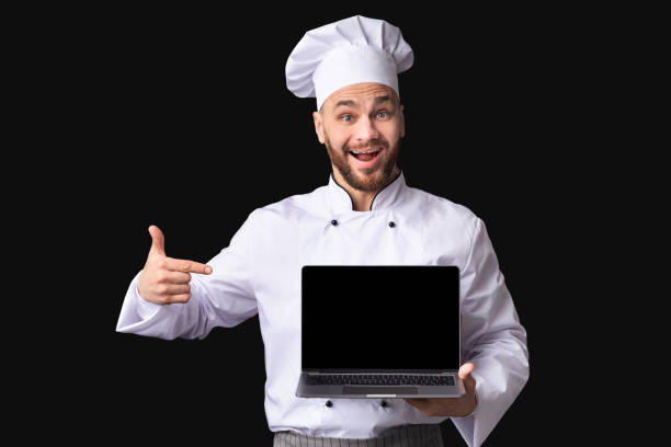 istock Male Chef Showing Laptop Pointing Finger At Screen, Black Background 2177089459