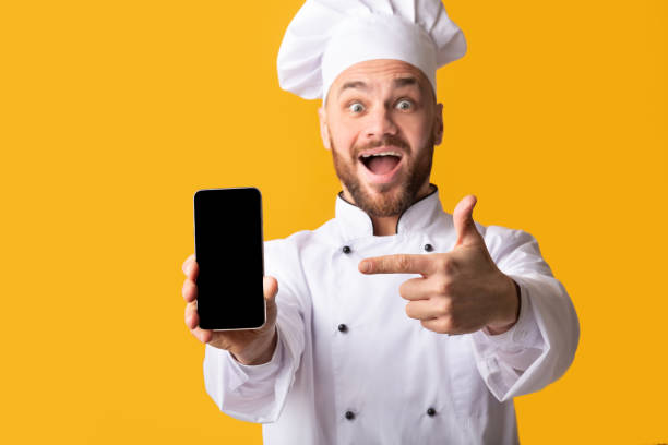 istock Chef Holding Phone Pointing Finger At Screen Over Yellow Background 2177089474