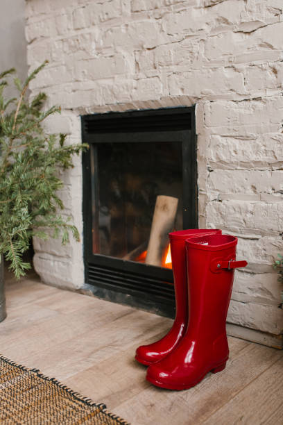 istock Red rubber boots stand near the Christmas fireplace 2177089514
