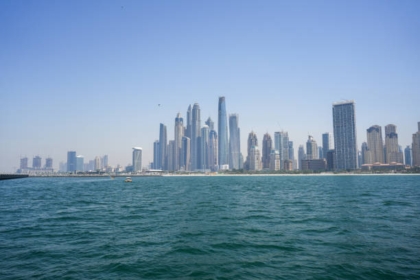 A stunning skyline of modern skyscrapers rising above the coastline, seen from the sea on a clear day, showcasing impressive urban architecture and waterfront views.