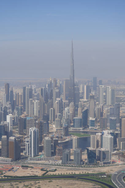 Aerial view of towering modern skyscrapers in a city skyline, with the tallest building emerging through a hazy atmosphere, showcasing the grandeur of urban architecture.