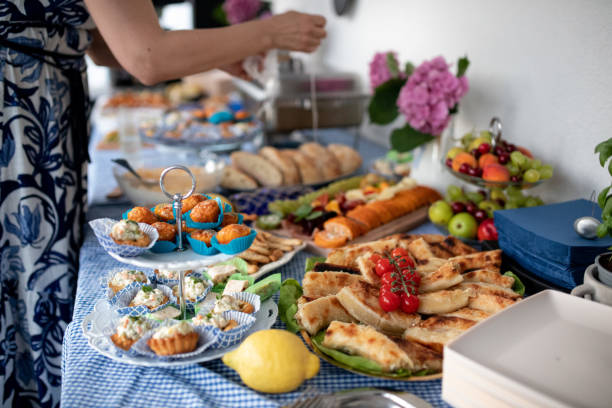 Woman taking food from beautifully decorated catering banquet table with different food snacks and appetizers