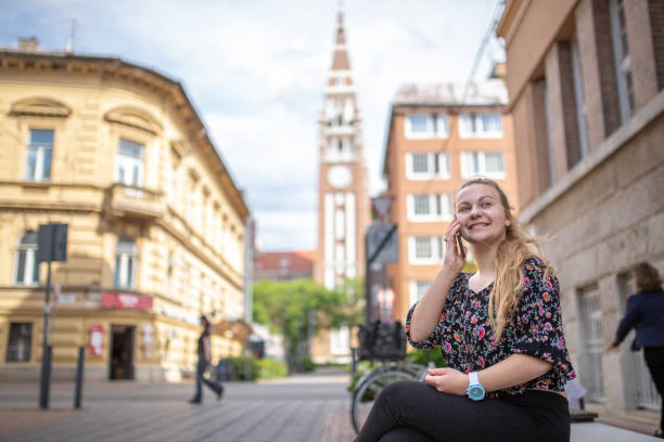 Young woman sitting  on a bench and using her smart phone