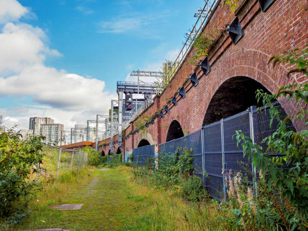 istock Salford, Manchester. Old brick railway arches surrounded by greenery under a cloudy sky. 2177098520