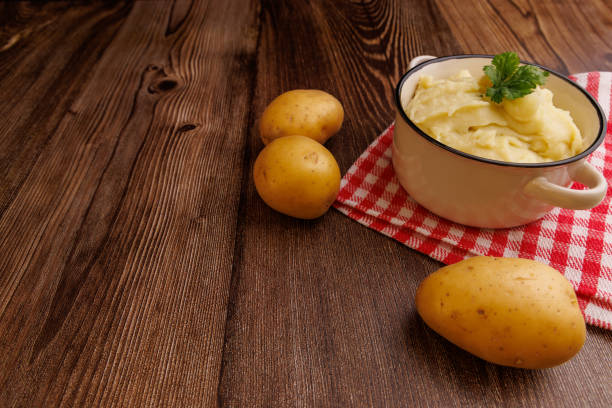 istock Freshly prepared mashed potatoes in a bowl with whole potatoes and a red napkin on a rustic wooden table, creating a homey atmosphere 2177098921