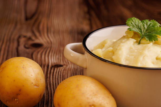 istock Freshly made mashed potatoes in a bowl with raw potatoes on a rustic wooden table, captured in a detailed close up for a cozy and homely feel 2177099144