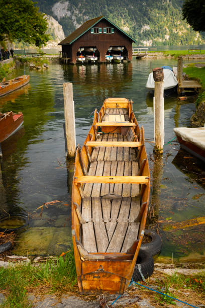 A wide shot of six rowing boats docked on the riverside, the water is still and calm.  The first two boats are crisply in focus, the rest slowly drift off into the background bokeh.