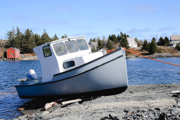 Beached boat in Nova Scotia, Canada safe in the harbor. Blue boat. Boat with windows. Boat on the rocks.