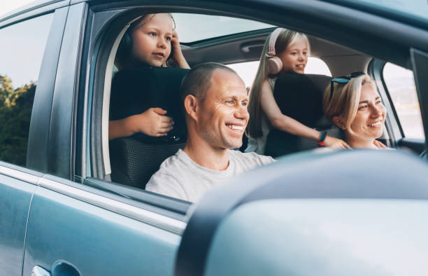 istock Happy smiling young couple with two daughters inside car during auto trop. They are smiling, and laughing during a road trip. Family values, tatraveling, automotive industry concept. 2177106384
