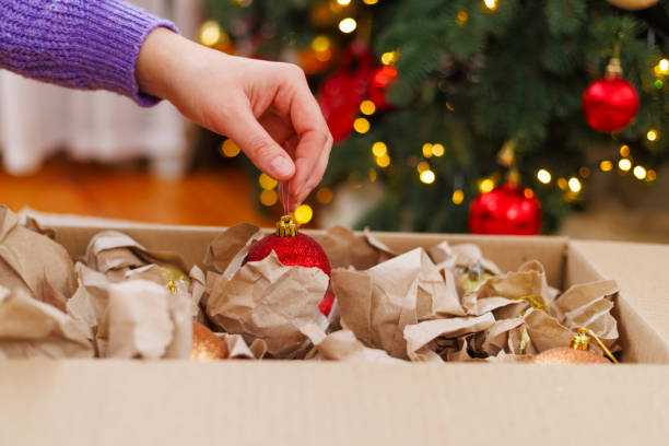 Hand unpacking red Christmas ornament from box