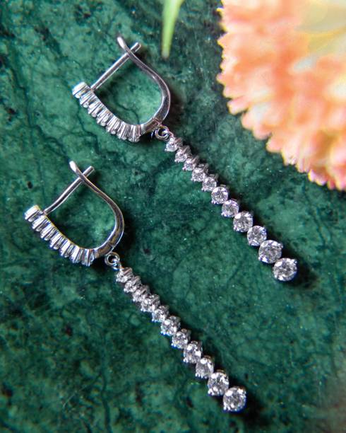 Pair of diamond earrings are lying on a green malachite stone Pair of white gold diamond earrings lying on green malachite stone hoops wedding stock pictures, royalty-free photos & images