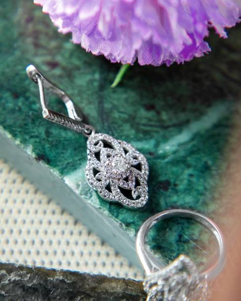 istock Silver earrings and ring with diamonds lying on green malachite stone 2177114705