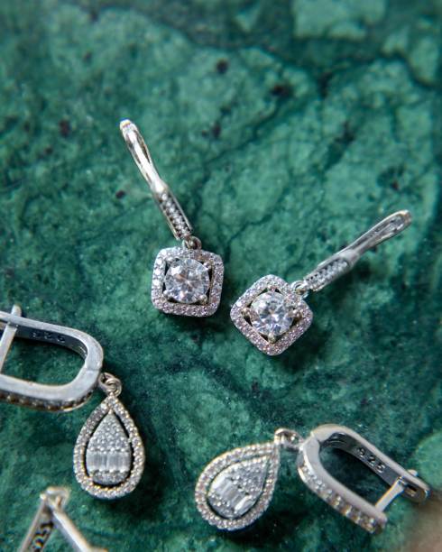 istock Sparkling silver earrings with diamonds on green malachite background 2177114793